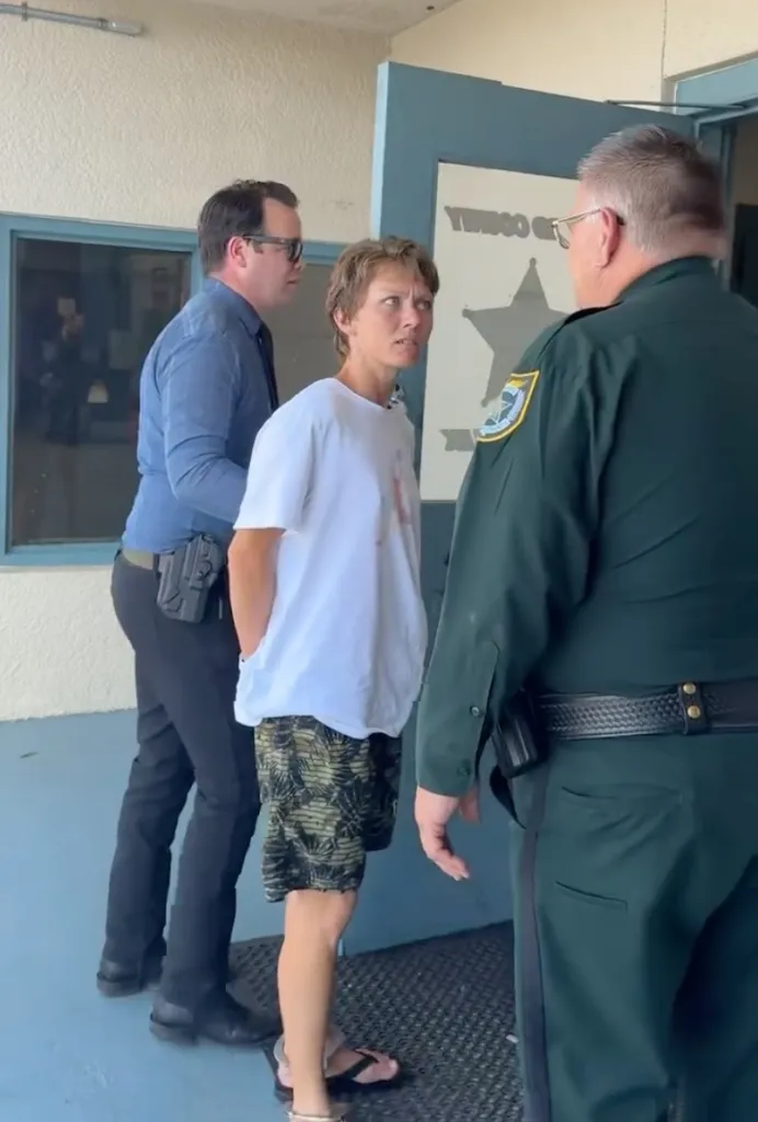 Linda Cutler being escorted by two police officers.