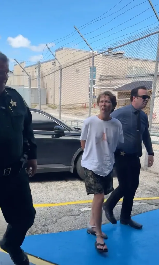 Linda Cutler in handcuffs being escorted by two police officers.