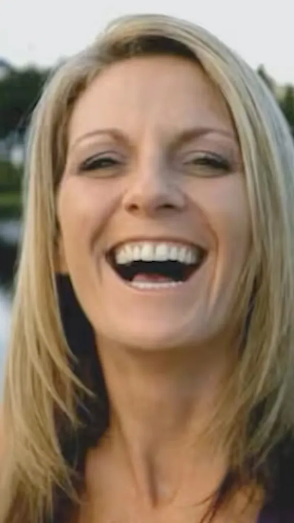 Close-up of Jodi Cowan, a fair-skinned woman with long blonde hair, laughing with her mouth open.