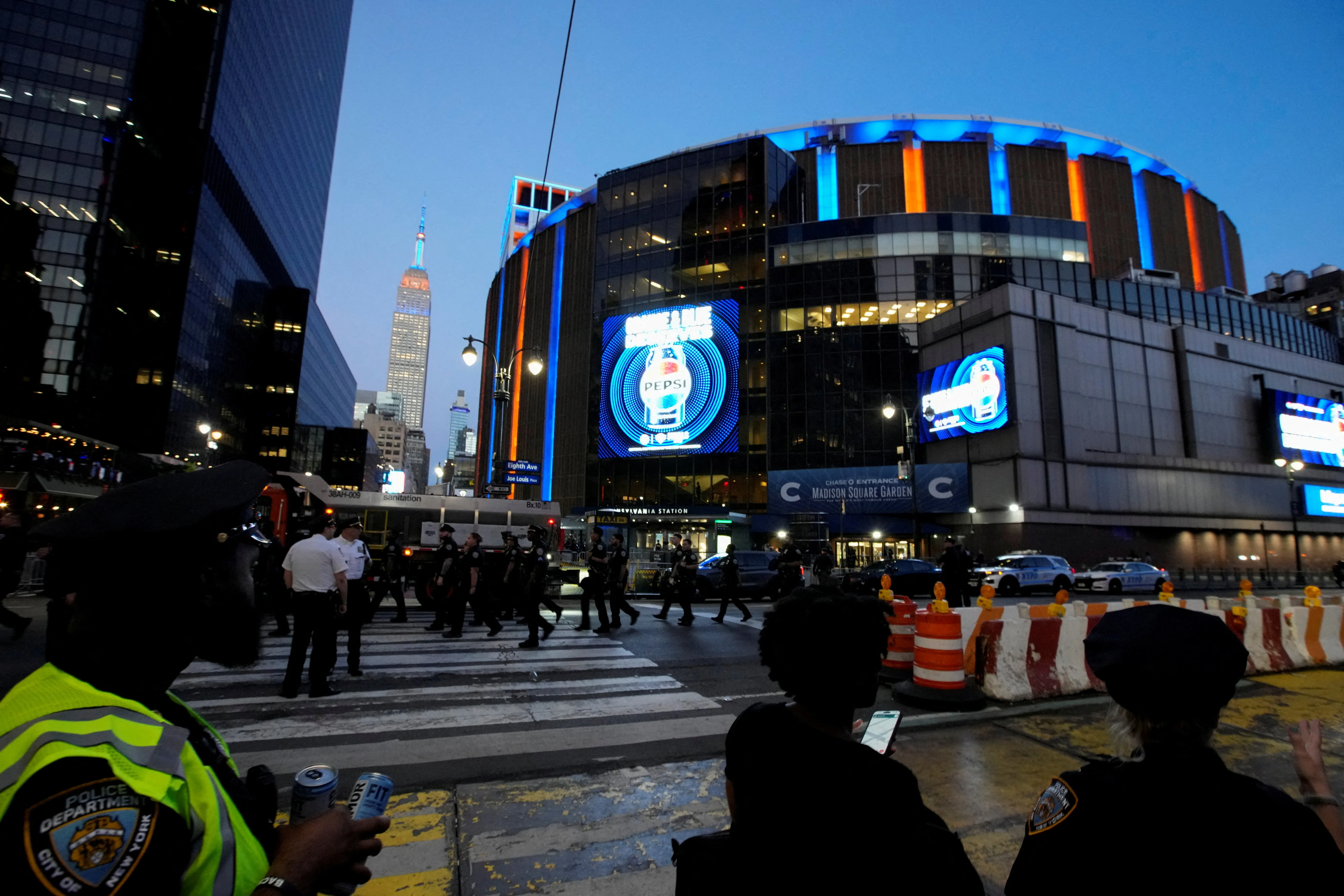 Police officers patrol outside Madison Square Garden and the Empire State Building, lit in blue and orange, during the NBA Finals in New York City.