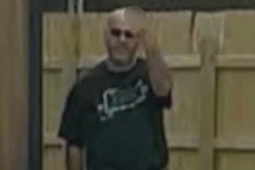 A man in a black T-shirt and sunglasses gives the middle finger.