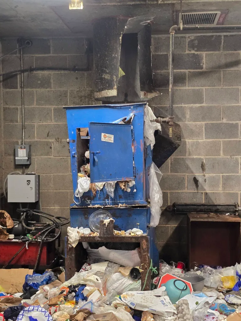 A trash chute and a large pile of garbage.
