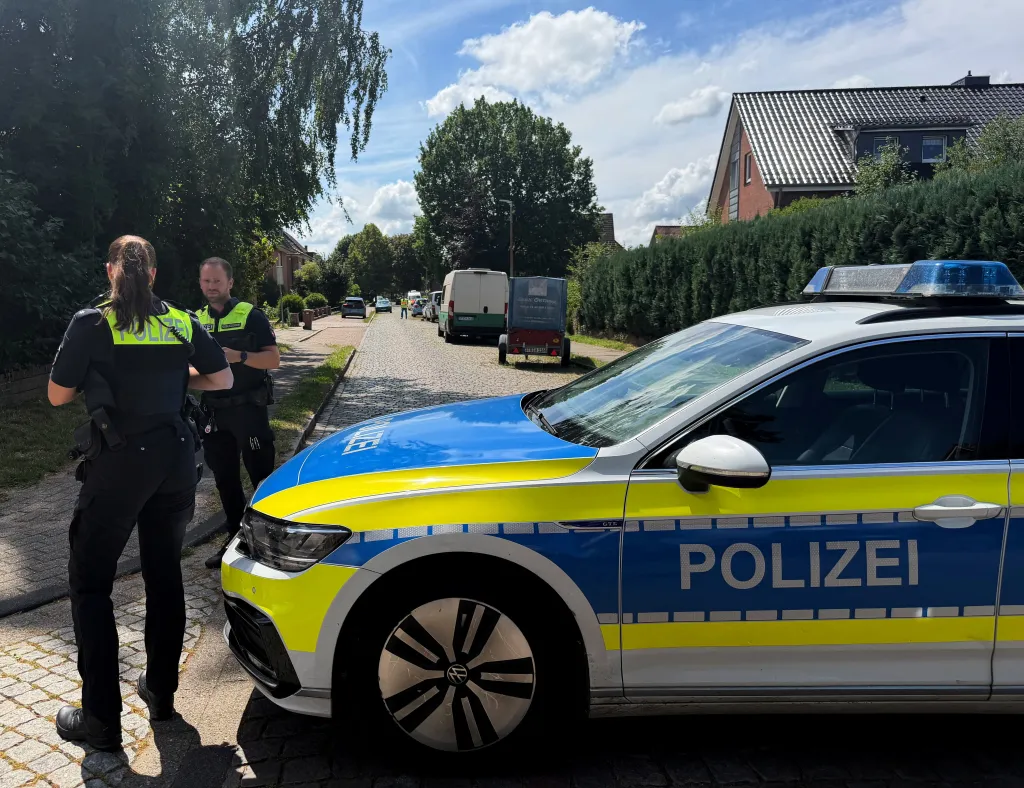Two police officers and a police car securing an area in a residential neighborhood.