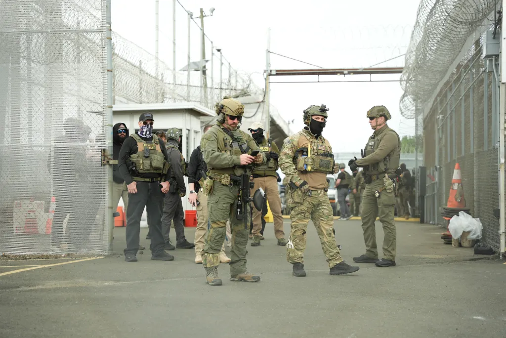 Federal law enforcement officers in tactical gear standing outside Delaney Hall detention center.