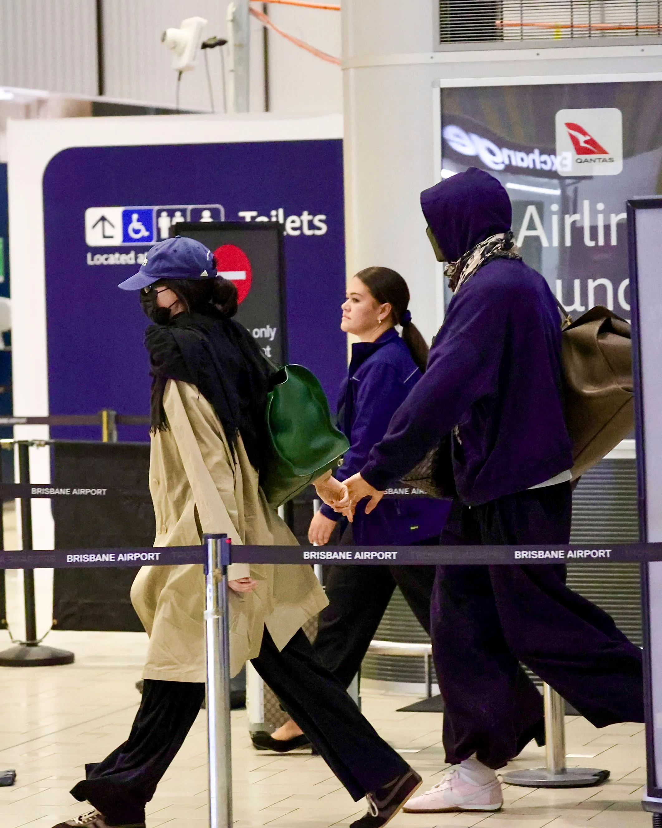 Kendall Jenner and Jacob Elordi walking through Brisbane Airport holding hands, attempting to go incognito in casual outfits.