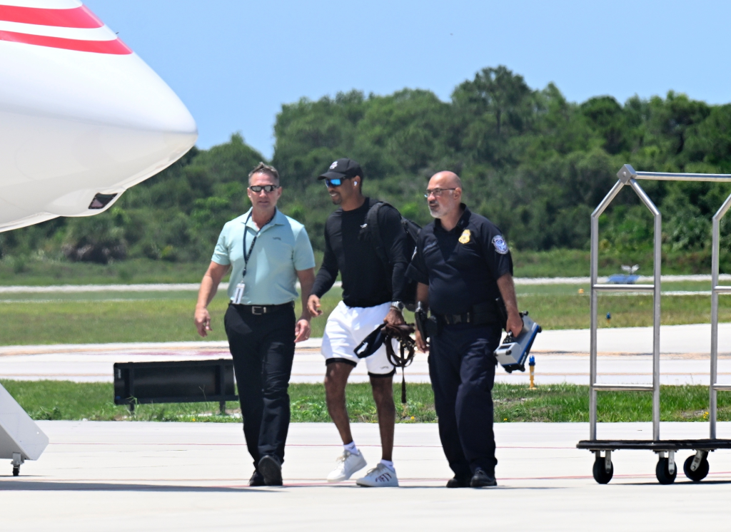 Tiger Woods arriving at a private airport after rehabilitation, walking with two men beside a private jet.