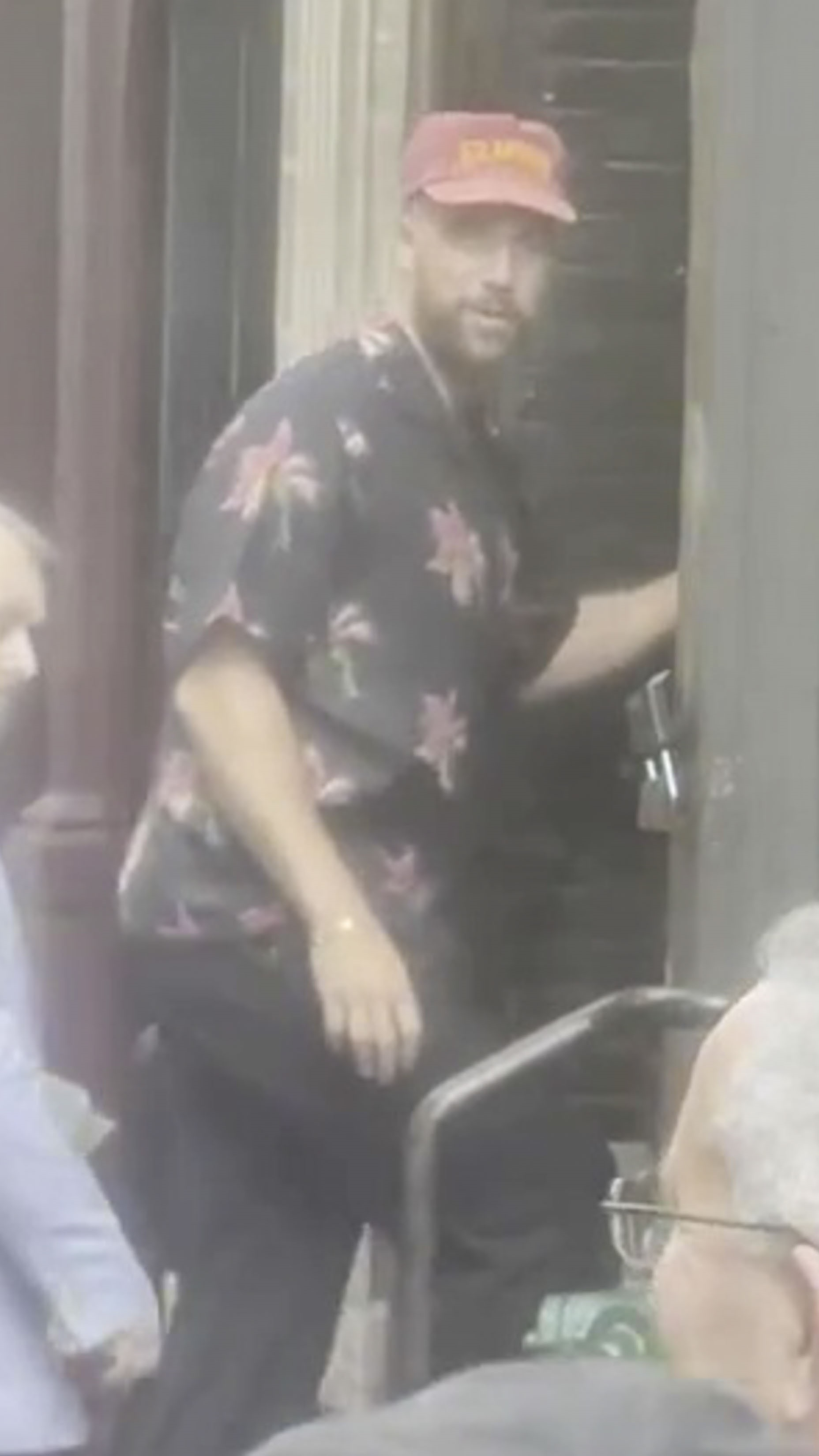Travis Kelce wearing a red cap and floral shirt.