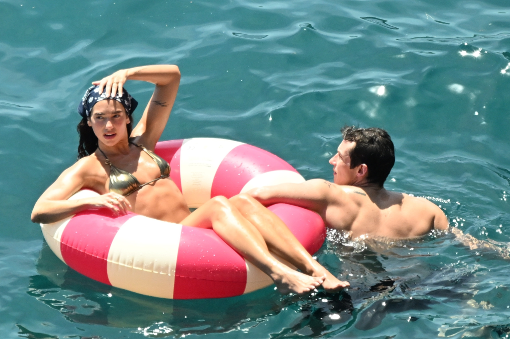 Dua Lipa and Callum Turner on an inflatable in the ocean during their honeymoon.
