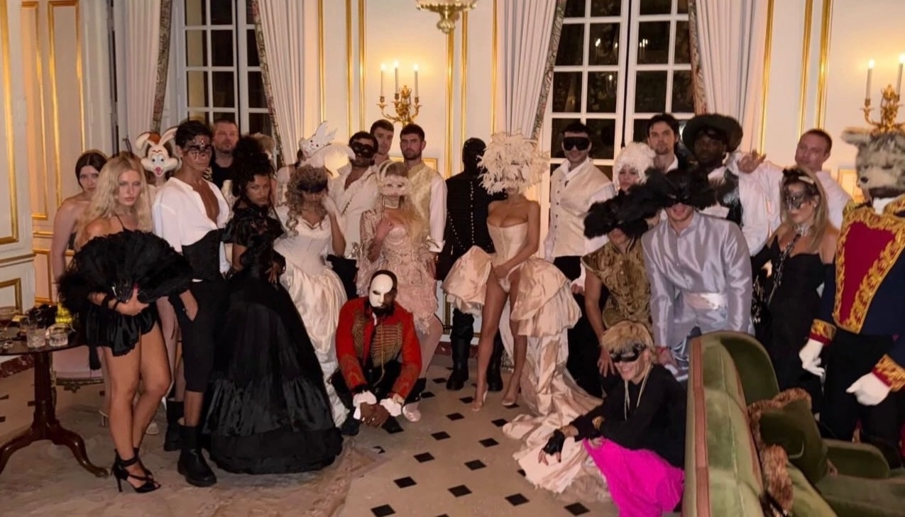 Kanye West and Bianca Censori pose with friends in period attire and masks at a lavish birthday celebration.