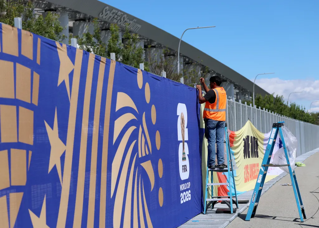 A worker installs a FIFA World Cup 2026 banner outside SoFi Stadium in Los Angeles.