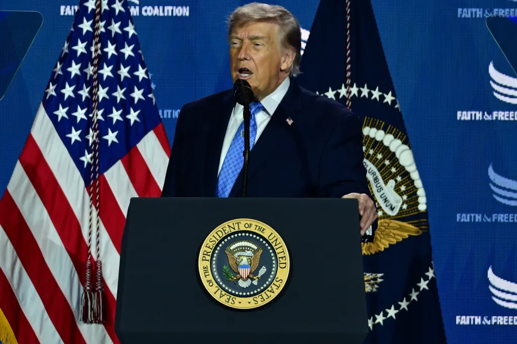 Donald J. Trump speaking at a podium with the Seal of the President of the United States, flanked by American flags and Faith & Freedom Coalition banners.