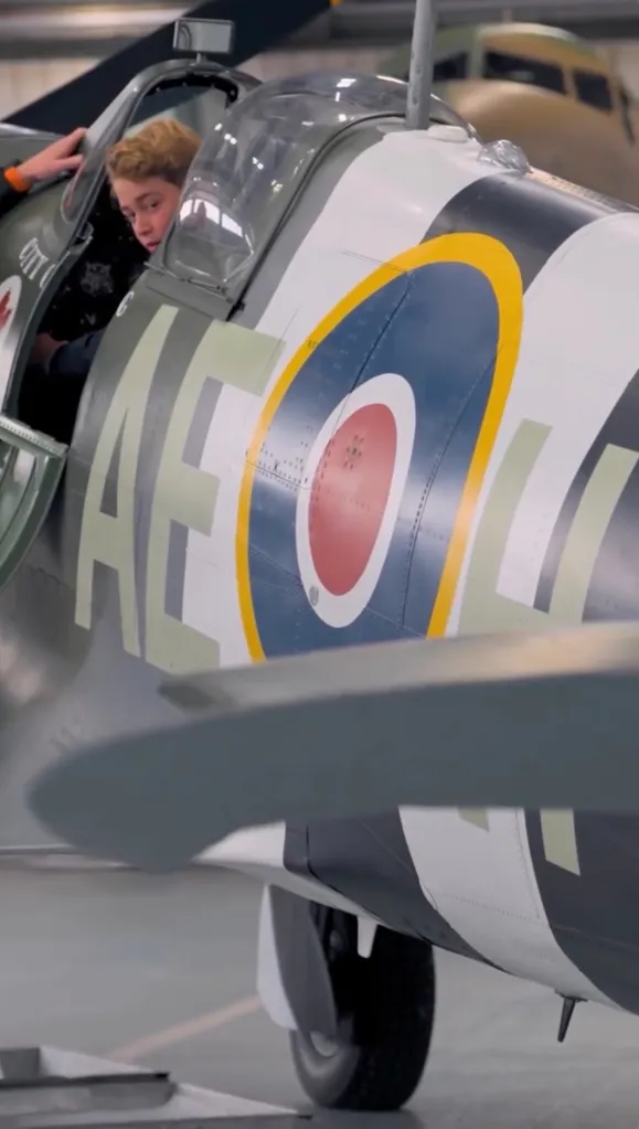 Prince George sitting in the cockpit of a Spitfire plane.