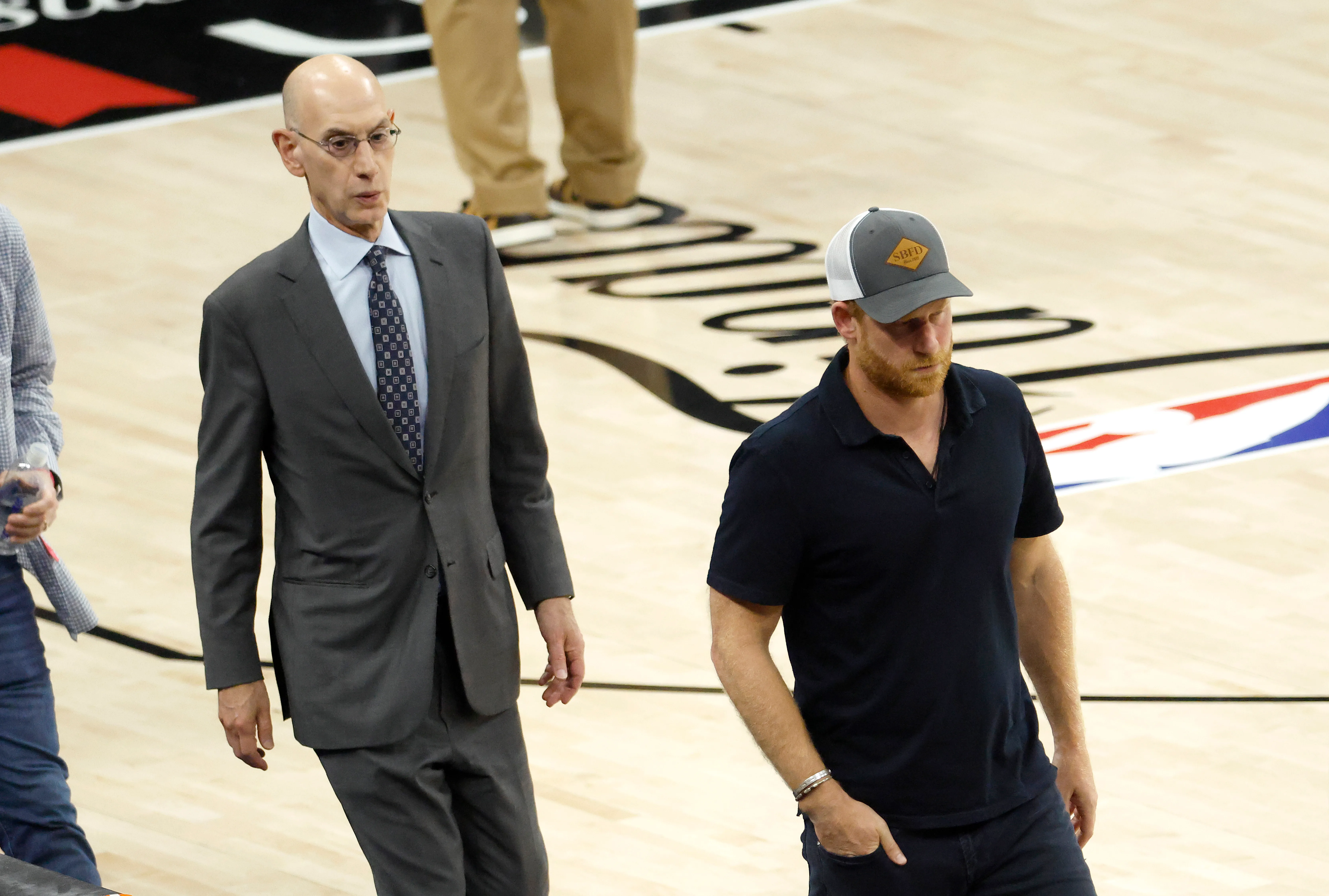 NBA Commissioner Adam Silver and Prince Harry walking across the court at halftime of game 5 of the 2026 NBA Finals.
