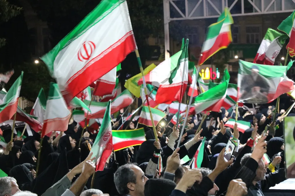 Iranian pro-government supporters waving national flags at a state-organized rally.
