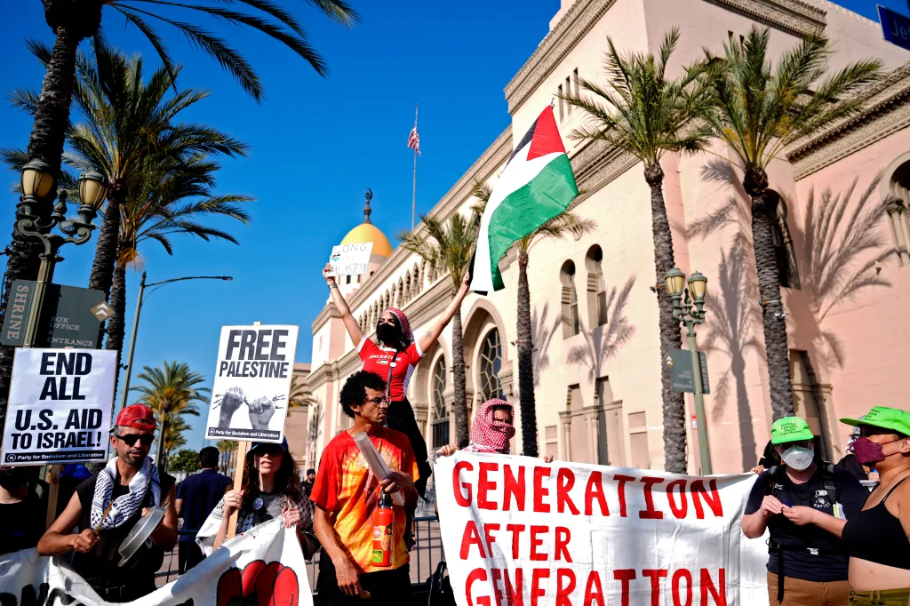 Pro-Palestinian demonstrators rally outside the Shrine Auditorium, holding signs saying 