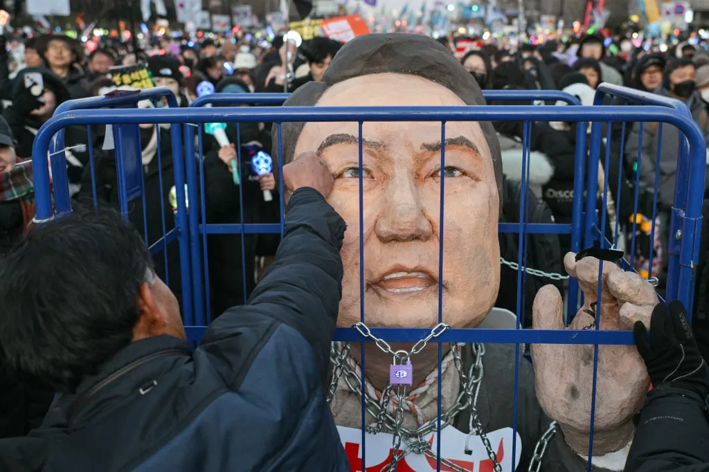 A protester punches an effigy of South Korean President Yoon Suk Yeol at a demonstration.