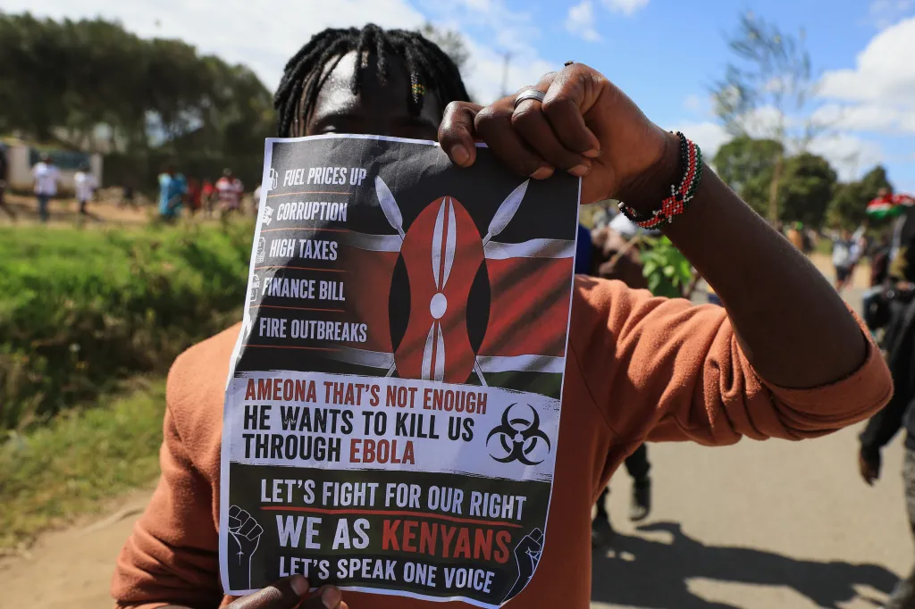 A protester holds a placard against a proposed Ebola quarantine center, listing grievances like 