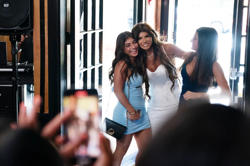 Gia Giudice and Teresa Giudice smile and embrace while a third woman smiles to the right.