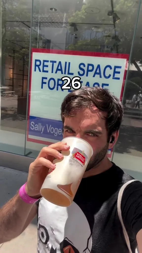 A man drinking from a large cup in front of a 