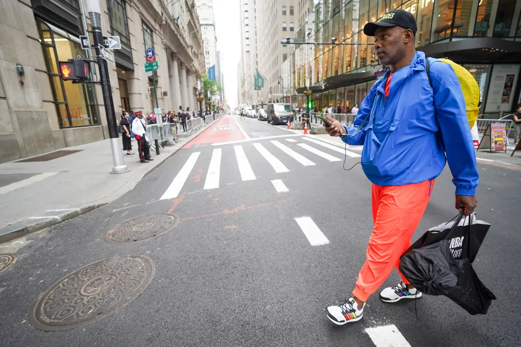 Roberts Samuel, CEO of Same Ole Line Dudes, holds an NBA Store bag while scoping out a parade route.