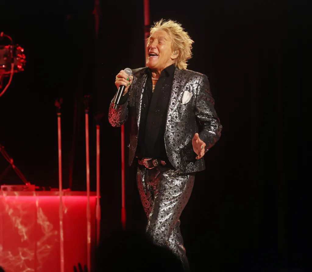 Rod Stewart singing into a microphone on stage.