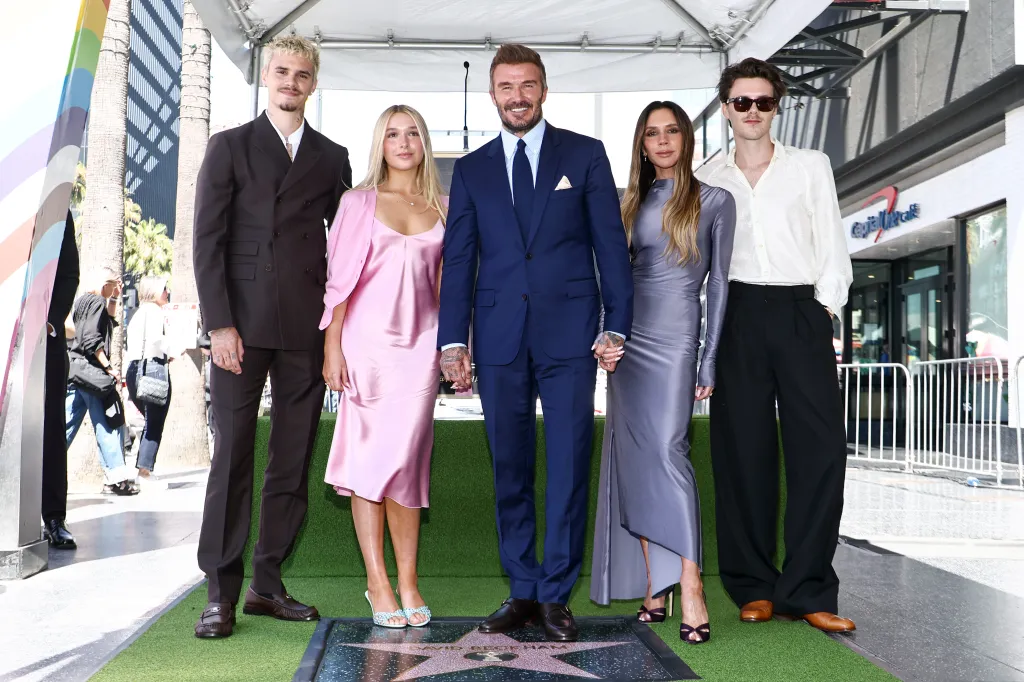 David Beckham, Victoria Beckham, and their children Romeo, Harper, and Cruz, standing on a green carpet around David Beckham's star on the Hollywood Walk of Fame.
