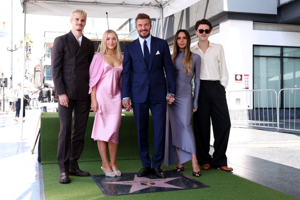 David Beckham, in a blue suit, blue tie and white shirt, Victoria Beckham, in a long grey dress, Harper Beckham in a pink dress and pink cardigan, Romeo Beckham in a brown suit, Cruz Beckham in a white shirt and black pants and black sunglasses.