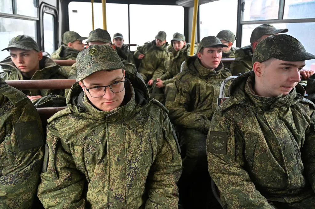 Russian conscripts in military uniform sit on a bus.