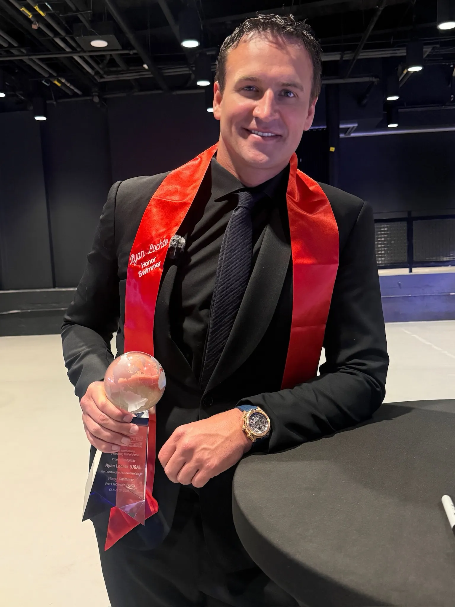 Ryan Lochte wearing a red sash that says 
