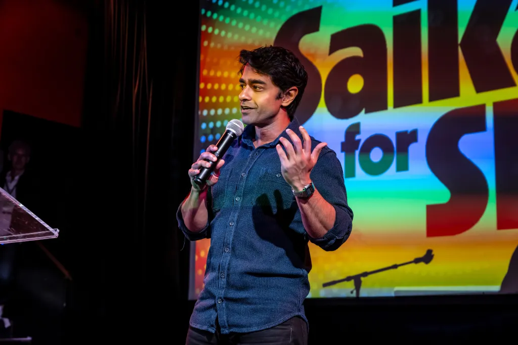 Saikat Chakrabarti speaking into a microphone with a colorful 