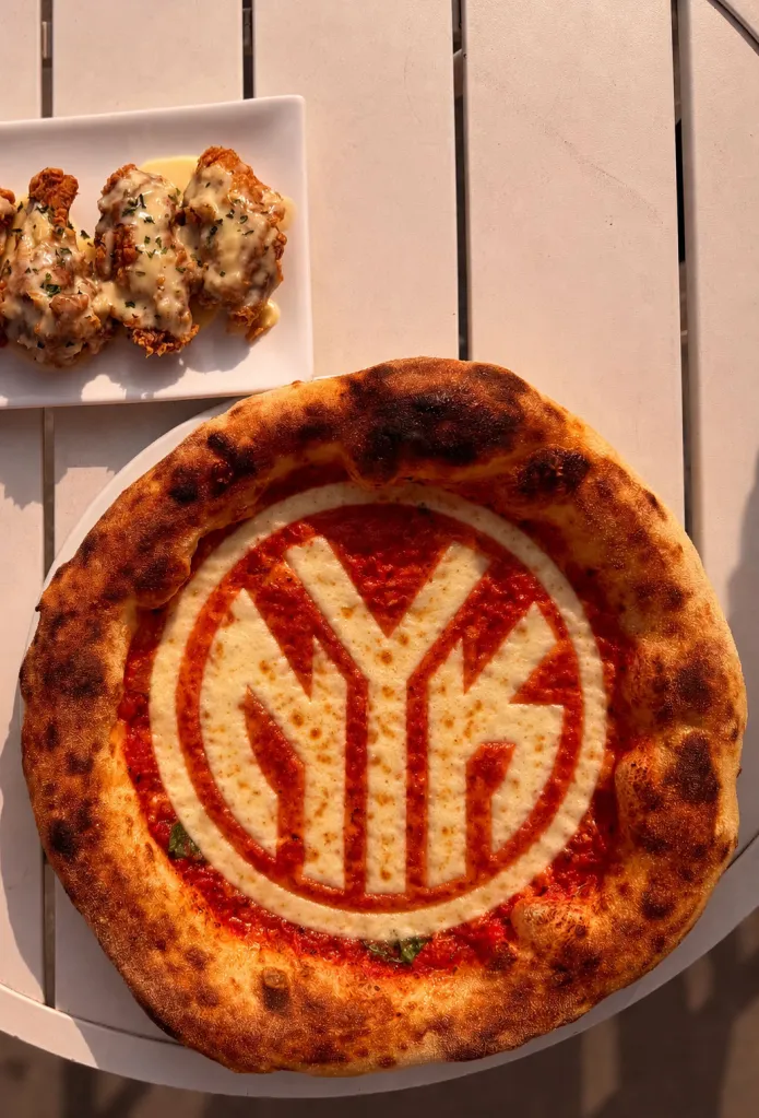 A pizza with the Knicks logo made of cheese, and a side of fried chicken.