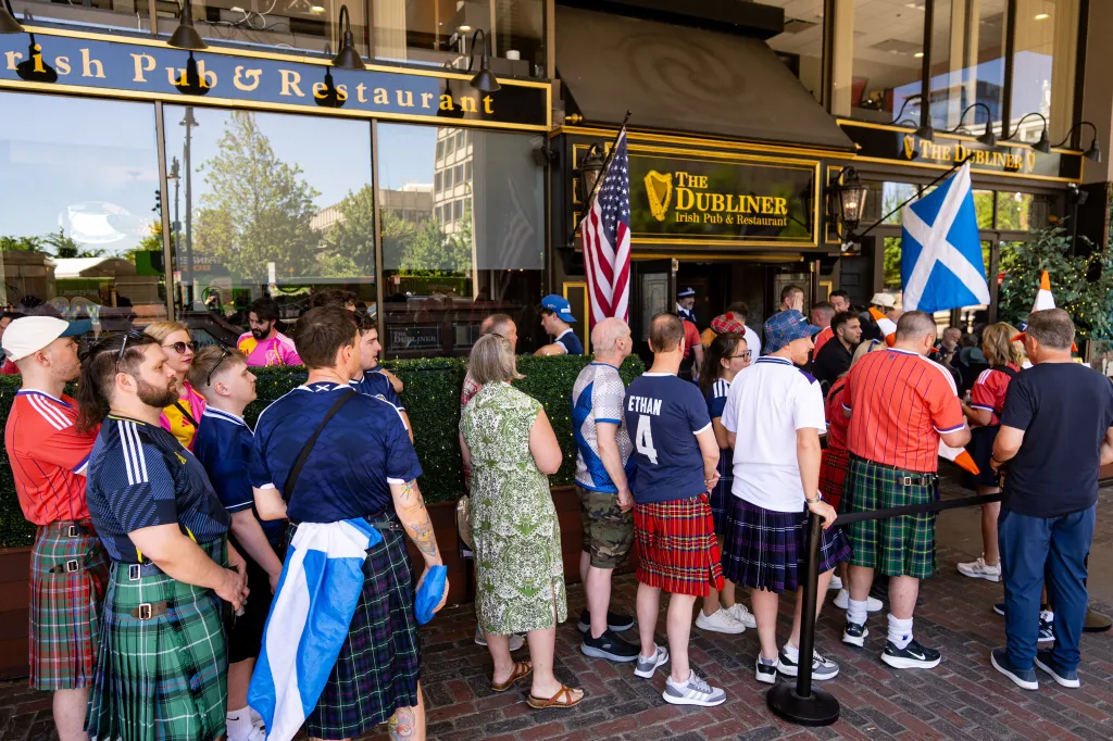 Scottish soccer fans wear jerseys and kilts while waiting outside The Dubliner Irish Pub & Restaurant.