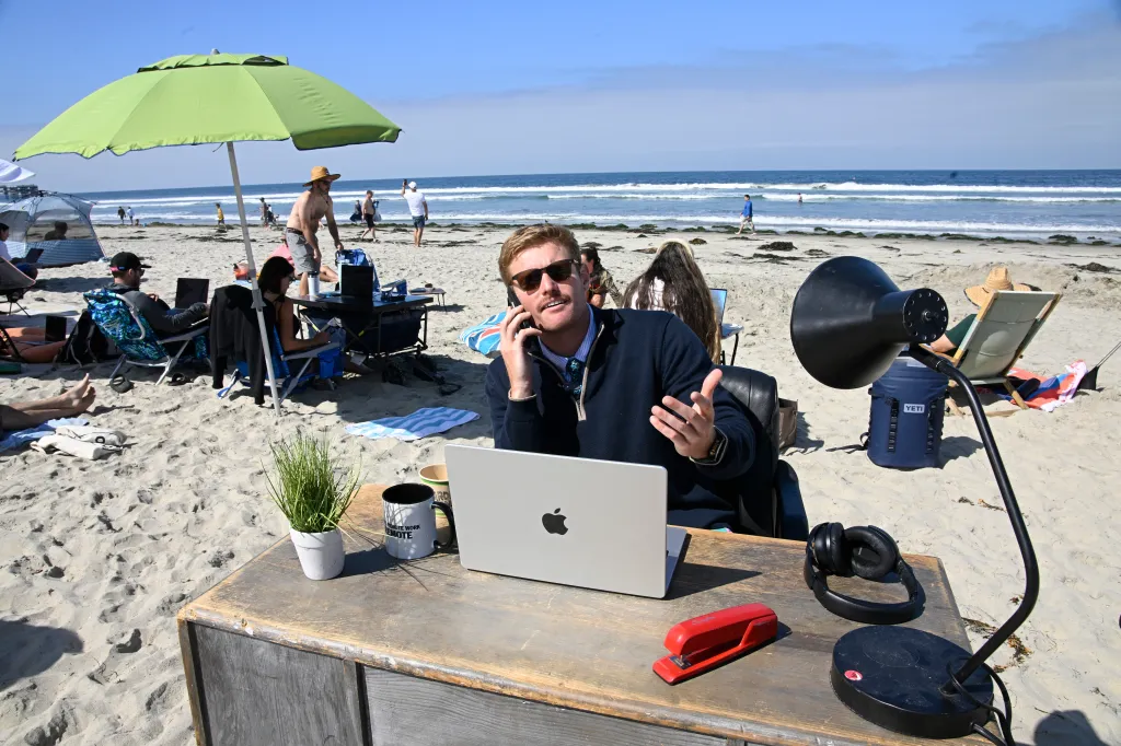 Scott Muirhead on the phone at a remote work event on the beach in San Diego.
