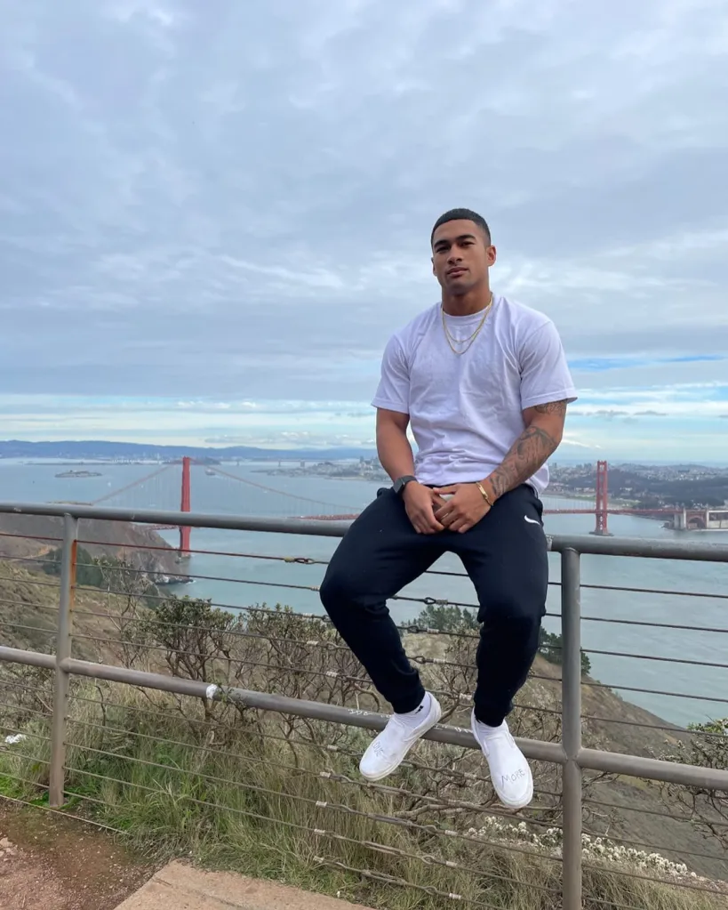 Sean Reifel sitting on a railing overlooking the Golden Gate Bridge and the San Francisco Bay.