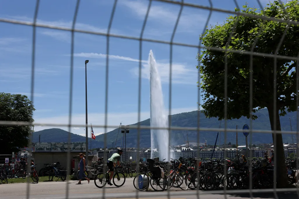 A protest against the upcoming G7 summit in Evian-les-Bains in France, in Geneva, with a water fountain and mountains in the background.