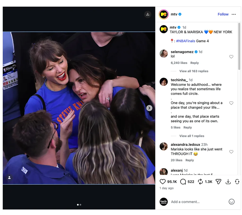 Taylor Swift in a blue shirt with red lipstick, embracing Mariska Hargitay, also in a blue shirt, at the NBA Finals.