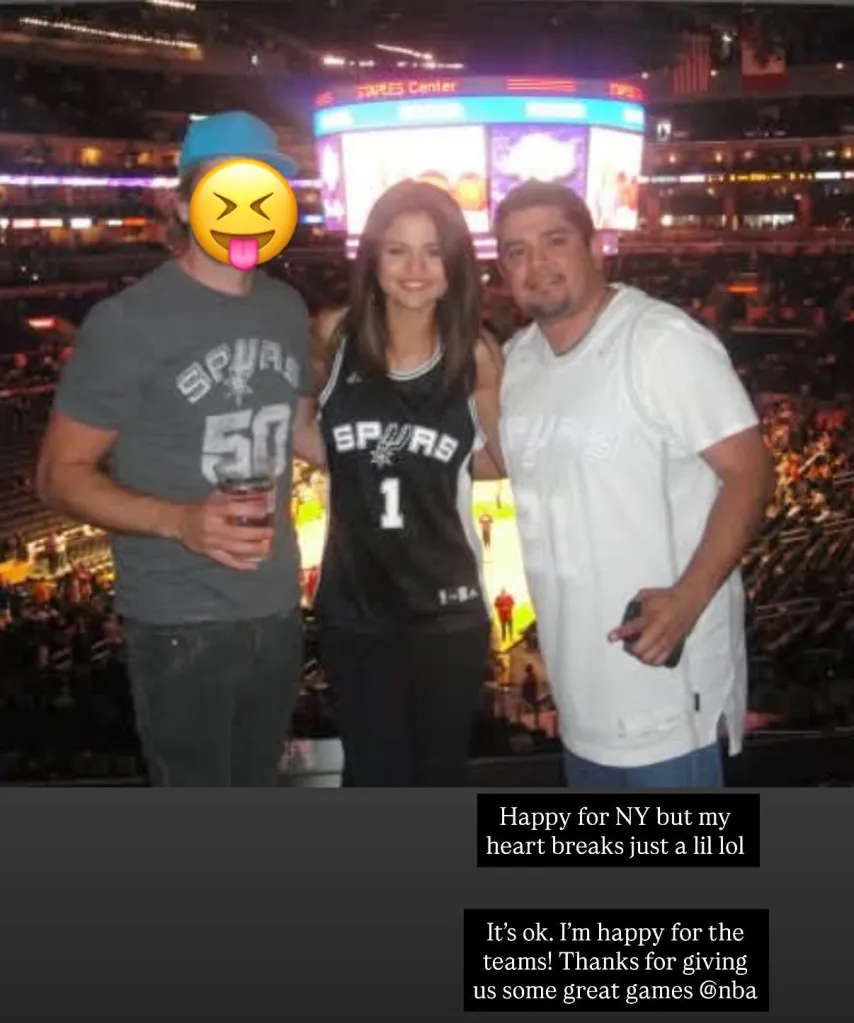 Selena Gomez posing with two men in the stands of a basketball game, all wearing Spurs gear.