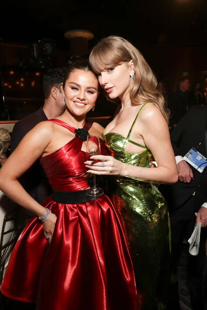 Selena Gomez in a red satin dress holding a drink and Taylor Swift in a green sequined dress at the Golden Globe Awards.
