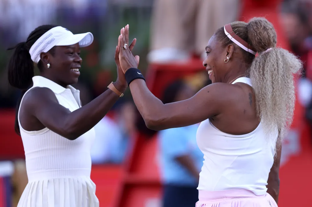 Serena Williams of the United States and Victoria Mboko of Canada high-five each other while smiling.