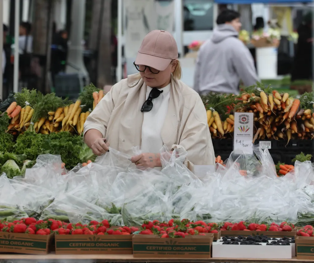 Sia wearing a baseball cap and sunglasses, shopping at the Studio City Farmers Market.