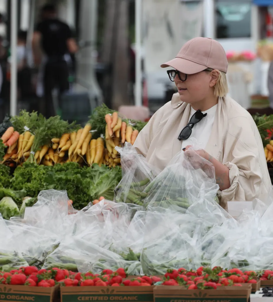 Sia selecting fresh produce at a farmer's market.