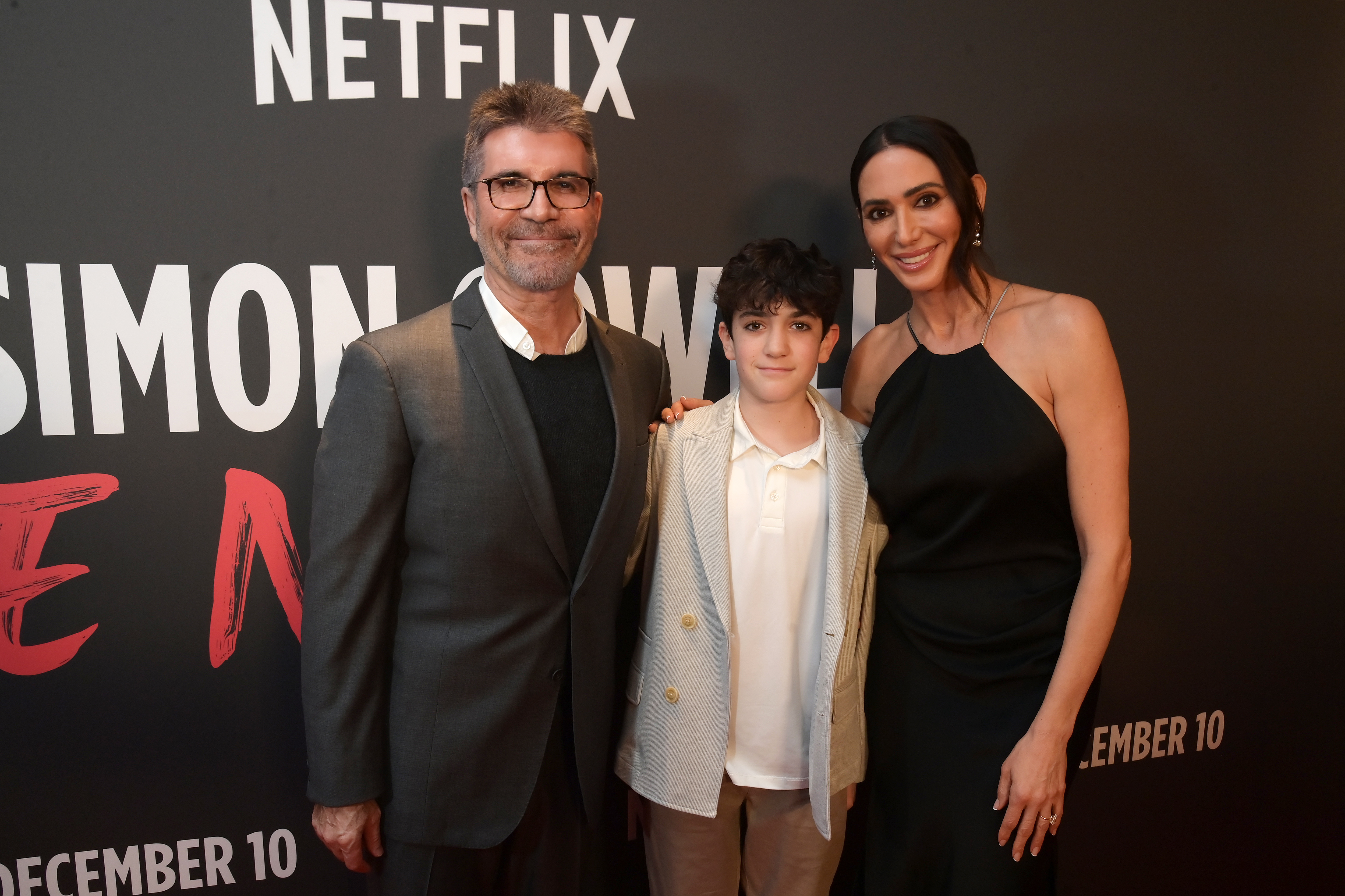 Simon Cowell, Eric Cowell, and Lauren Silverman smiling at a red carpet event.