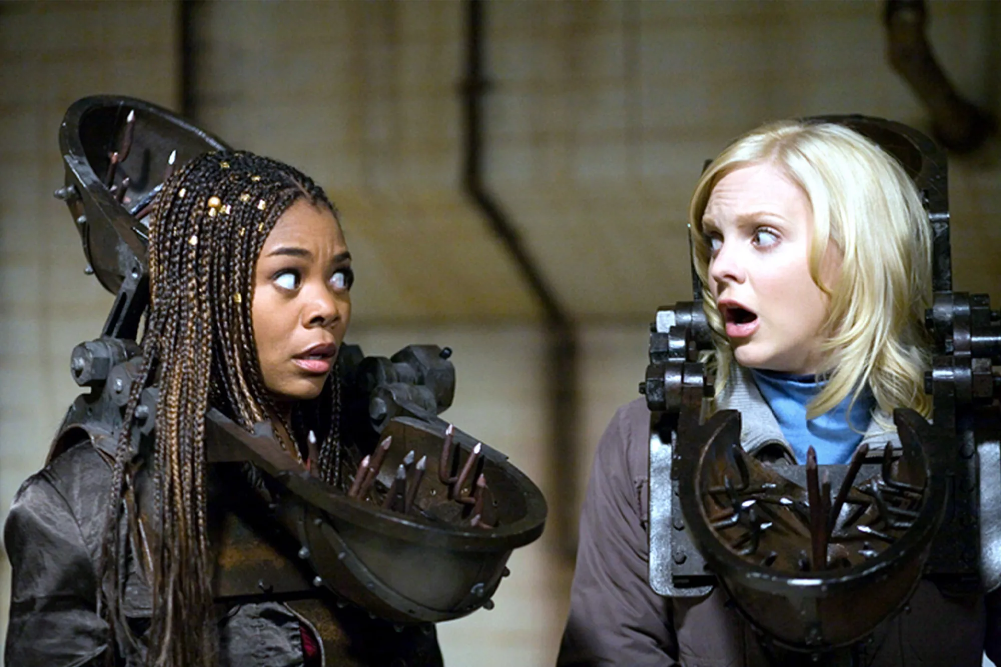 Two women in torture devices look horrified.