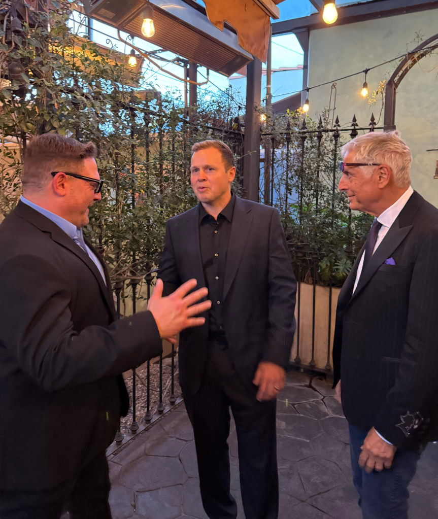 Spencer Pratt and two other men in suits talking at an election night event.