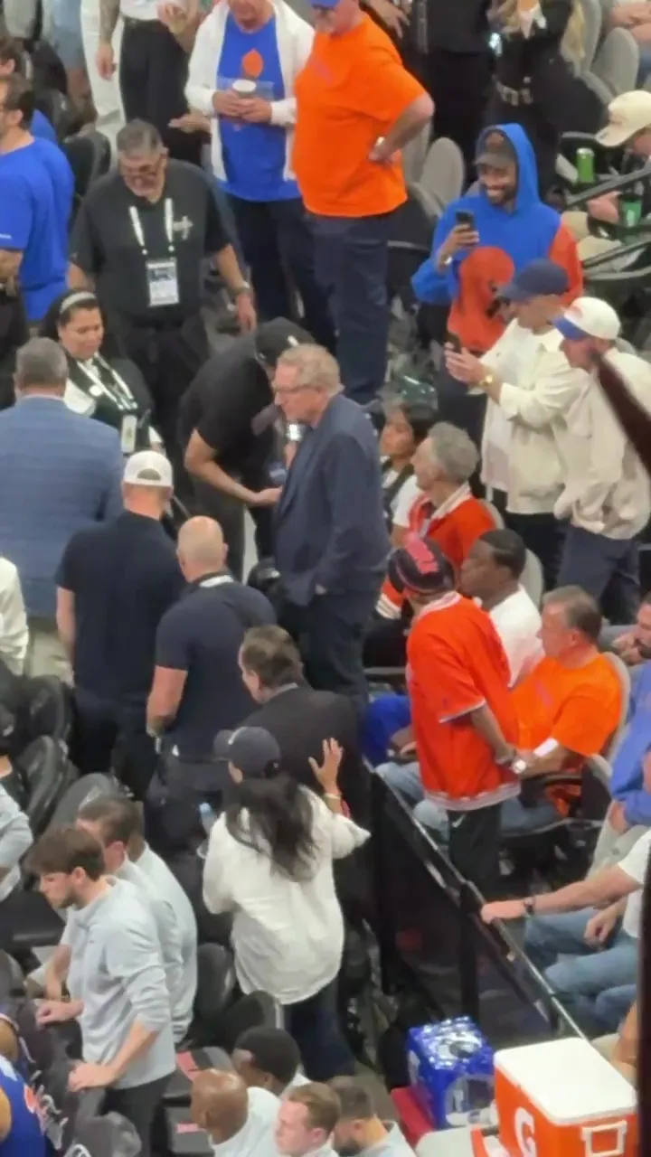 A high-angle shot of Spike Lee walking through a crowd at a basketball game.