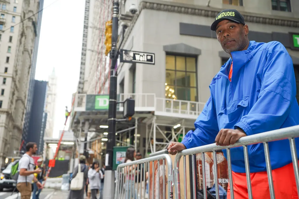 Roberts Samuel, founder of Same Ole Line Dudes, standing by a barricade at the corner of Wall Street.