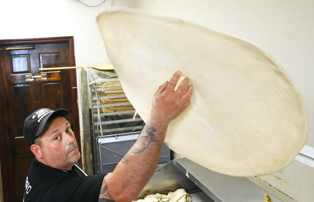 A man spinning a round pizza dough