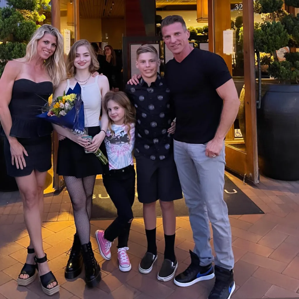 Steve and Sheree Burton with their three children, one daughter holding a bouquet of flowers.
