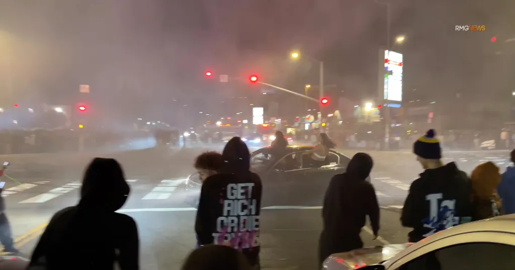 Street takeover with fireworks and crowds at an intersection.