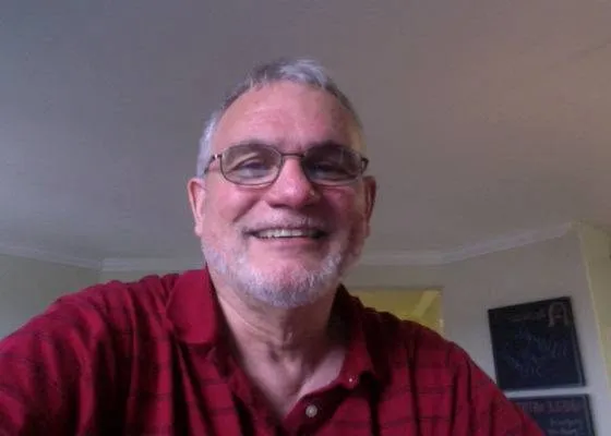 Jim Birge, a man with gray hair and beard, wearing glasses and a red plaid shirt, smiles.
